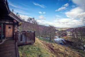 View from a luxury log cabin deck at Eagle Brae overlooking the Scottish Highlands valley near Inverness with wooden lodges and rolling hills