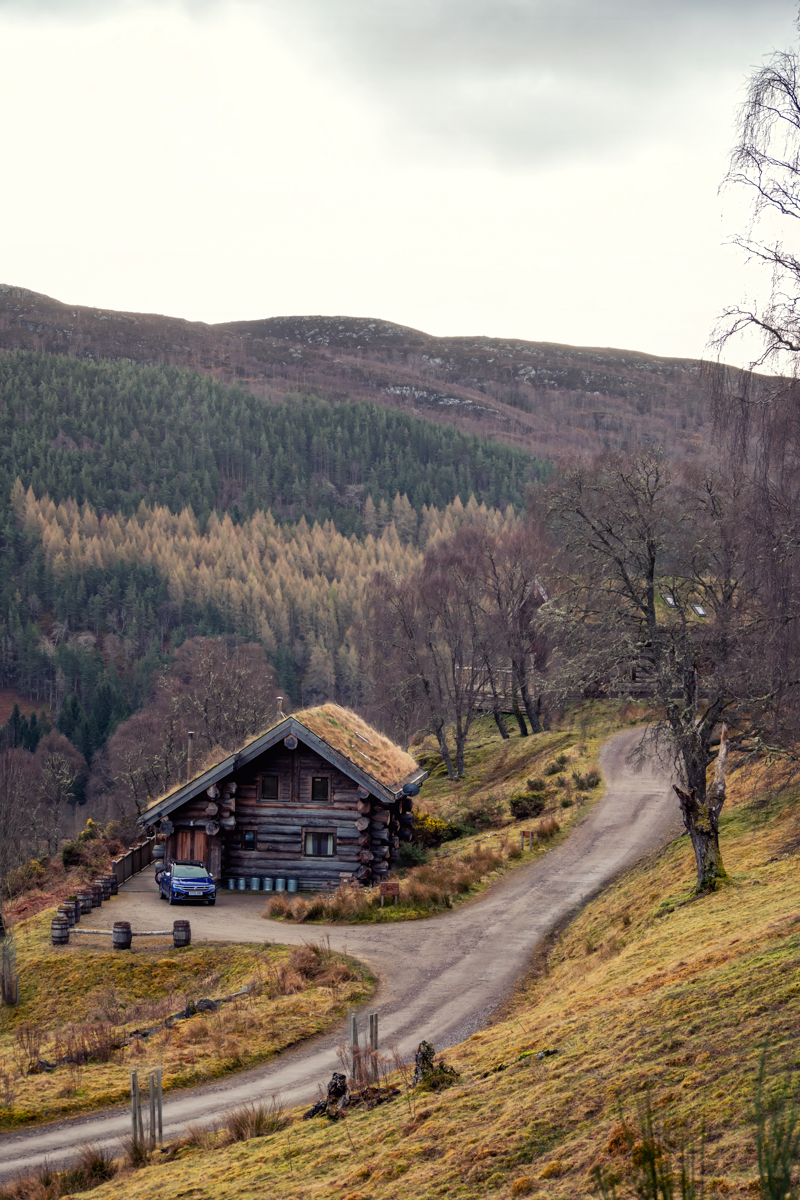 Eagle Brae luxury log cabin beside a winding Highland road in Struy near Inverness surrounded by forested hills in the Scottish Highlands
